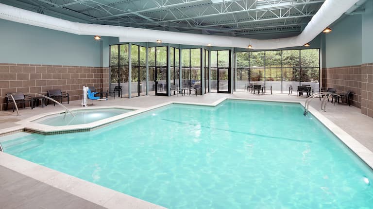 Indoor pool with chairs and windows