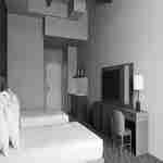 Guest room with two beds, entry to room, work desk and chair with wall screen above