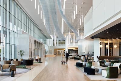 People Sitting in Lobby Area and a Person Pushing a Luggage Carrier