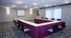 Meeting Room With Presentation Screen, Large Window With Sheer Drapes, Wall Art, and Seating For 10 at U-Table