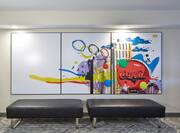 Colorful Lobby Art Feature on Wall by Two Black Ottomans