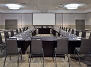 Meeting Room With Projector Above Hollow Square Table With Black Chairs and Projector Screen