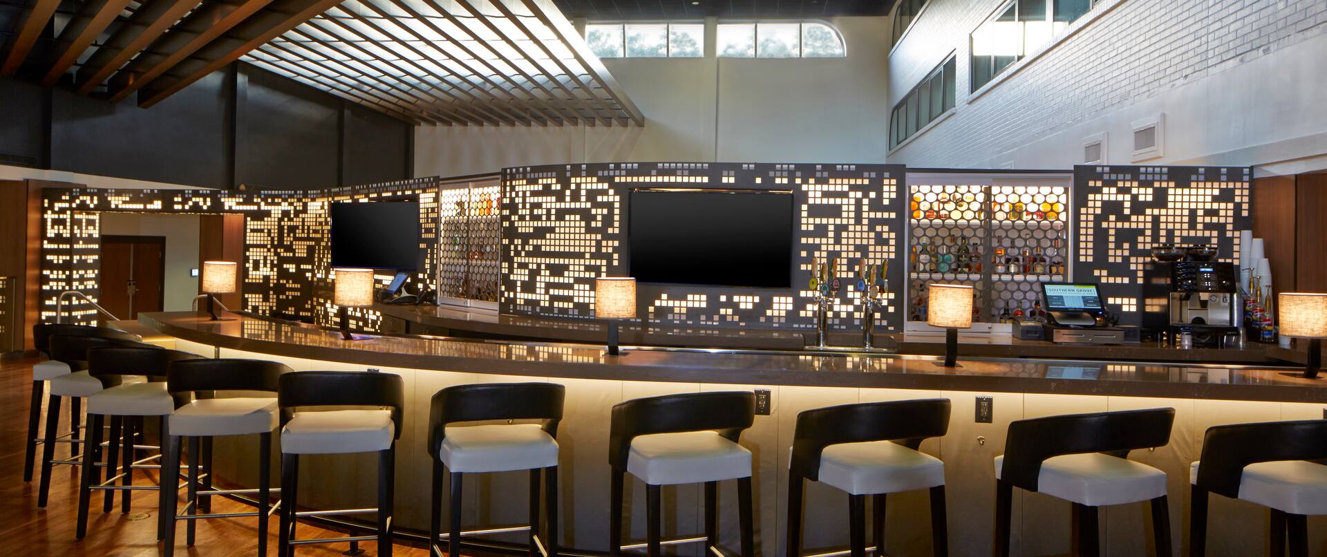 Counter Seating at Fully Stocked Bar With TVs and Illuminated Lamps