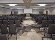 Meeting Room Arranged Theater Style With Rows of Chairs Facing Projector Screen and Podium