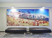 Brightly Lit Photo Triptych on Wall by Two Black Ottomans in Lobby