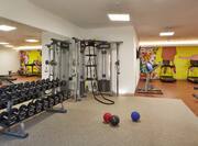 Fitness Center With Mirrored Wall, Free Weights, Weght Balls, Weight Machine in Corner, Cardio by Large Wall Mural, and Weight Bench