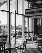 Sunny restaurant interior with wooden chairs, patterned floor, and patio view.