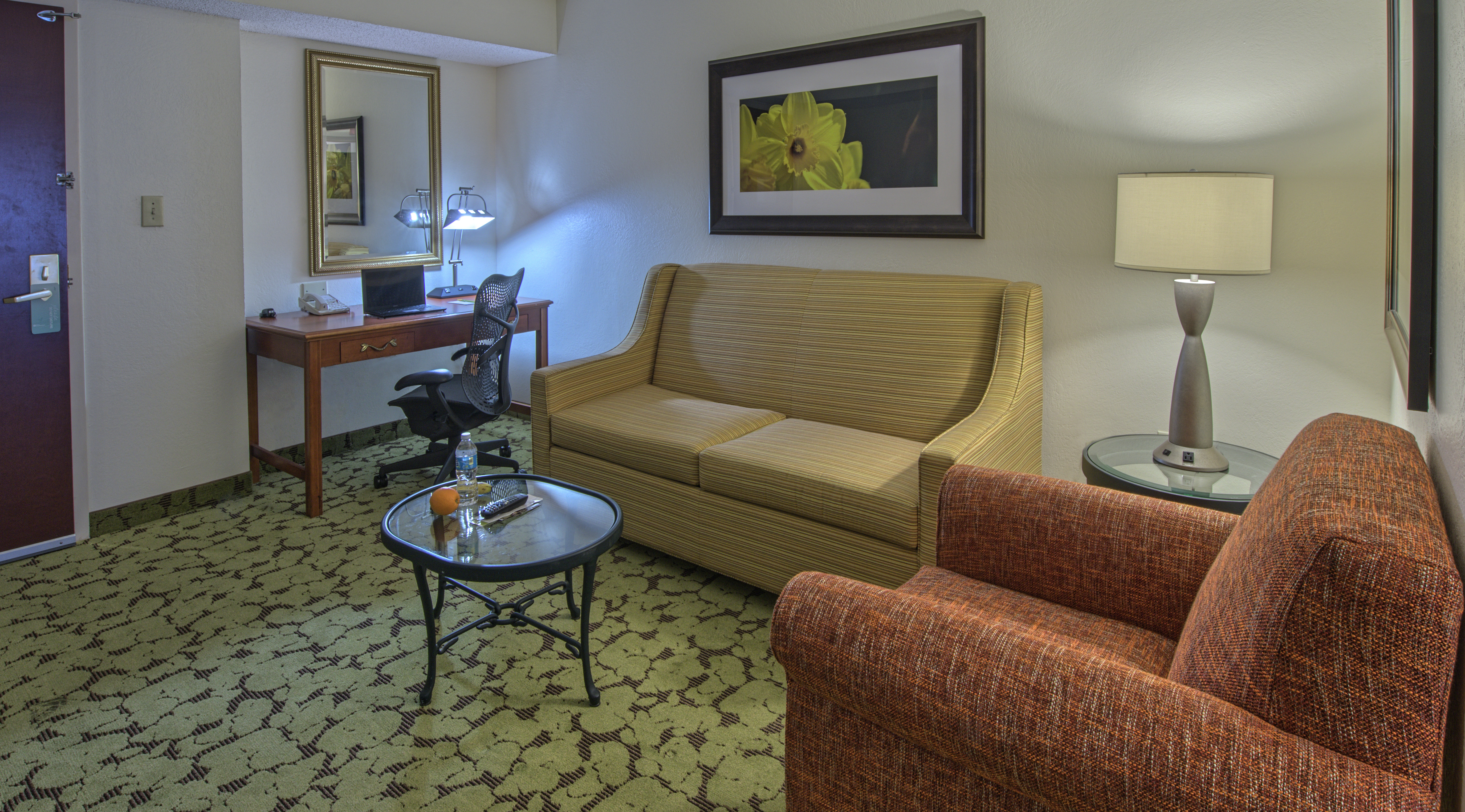 Seating area in accessible suite with couches and work desk.