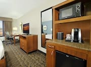 In-room hospitality center with microwave, coffee maker, and fridge with view of TV and work desk.