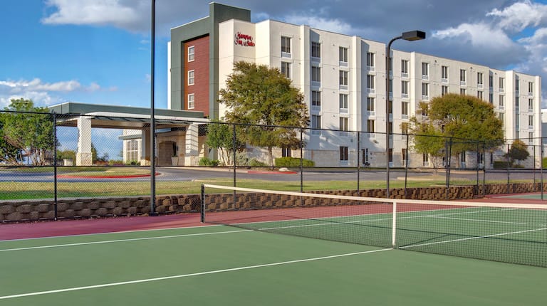 view of hotel exterior and tennis courts 