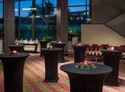 Candles and Flowers on Round Tables With Black Covers in Pre-Function Space With Soft Seating and Large Windows With Sunset View