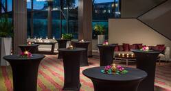 Candles and Flowers on Round Tables With Black Covers in Pre-Function Space With Soft Seating and Large Windows With Sunset View