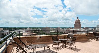 Penthouse Patio View of the Texas State Capital Building With Table, Chairs, and Loungers