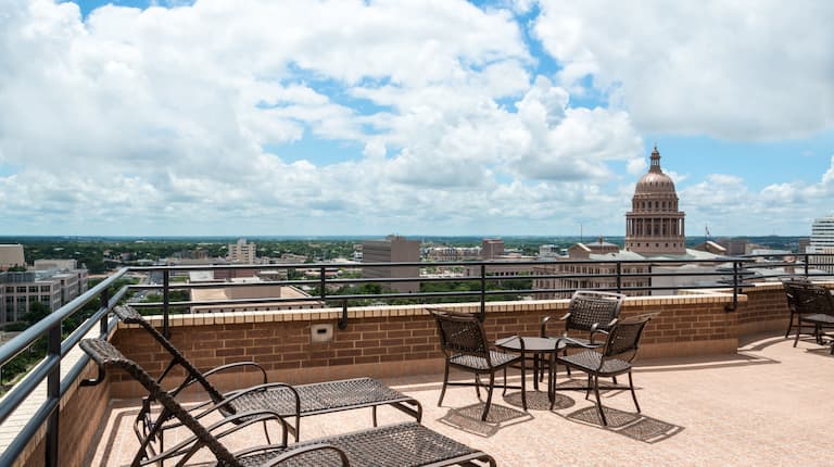 Penthouse Patio View of the Texas State Capital Building With Table, Chairs, and Loungers