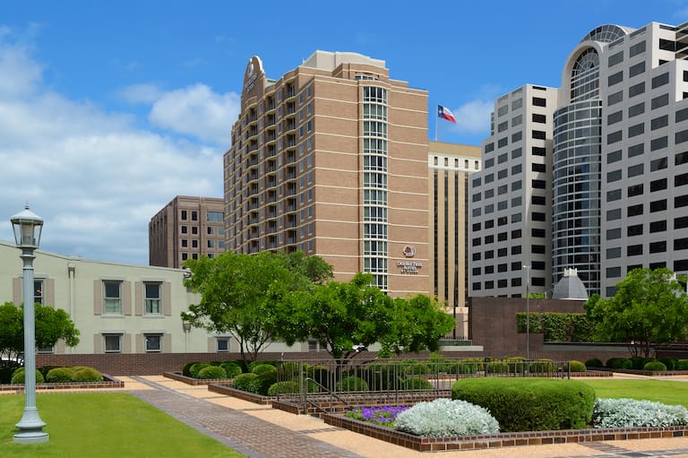 Vista diurna dell'esterno dell'hotel, della segnaletica, della bandiera e del paesaggio dal Campidoglio dello Stato del Texas 