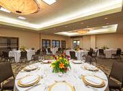 Round Tables in Ballroom With Place Settings, Flowers and Candles on White Tablecloths