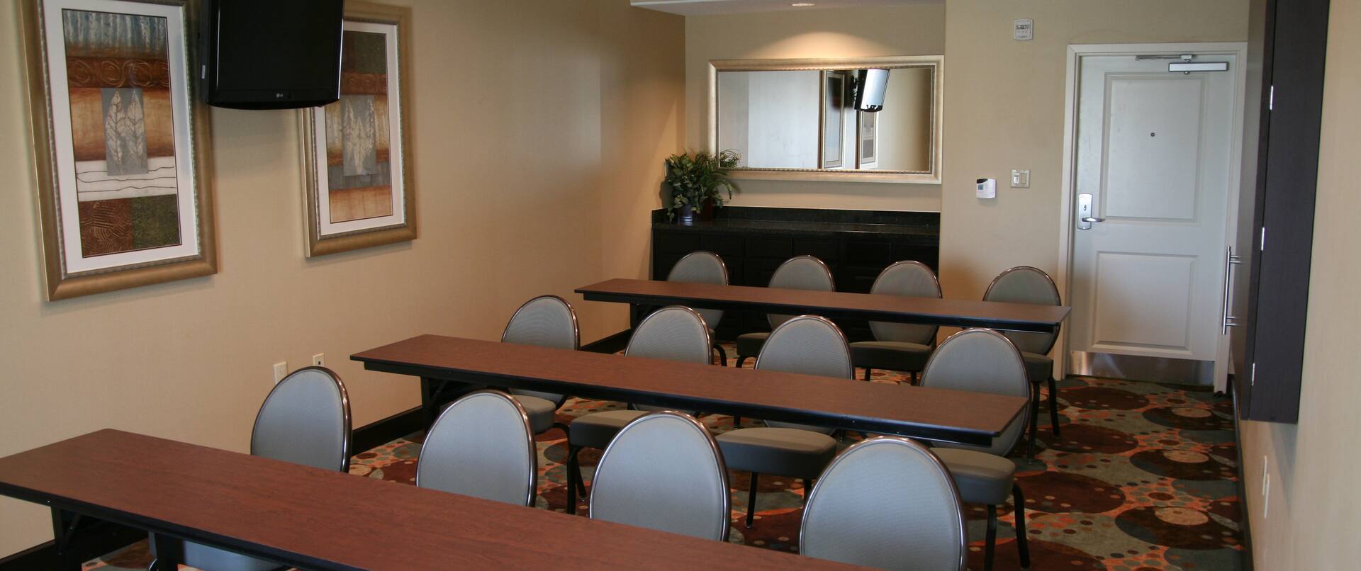 Classroom Setup in Meeting Room With Tables, Chairs, Wall Art, and Entry Door