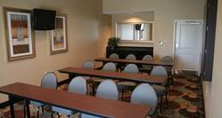 Classroom Setup in Meeting Room With Tables, Chairs, Wall Art, and Entry Door