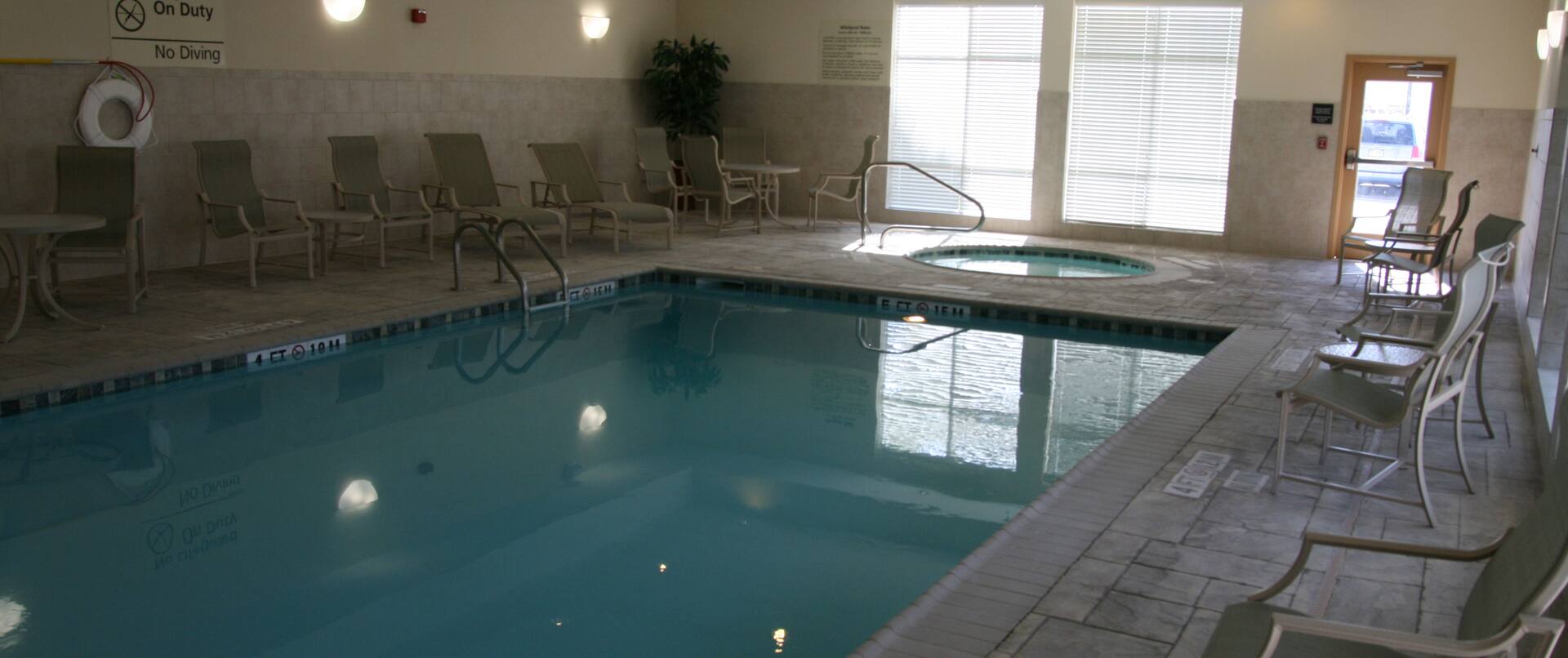 Longers, Tables, and Chairs by Indoor Pool Area With Window