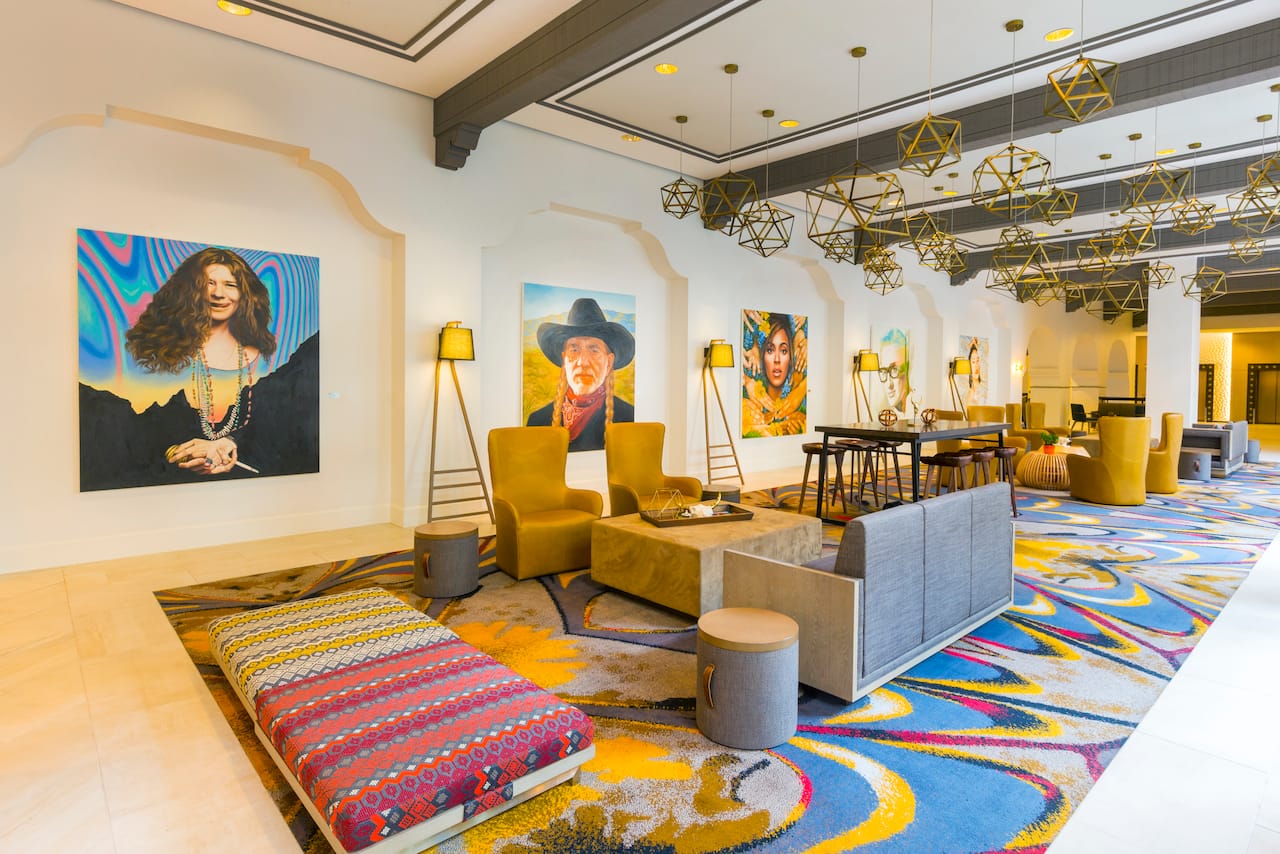 Tables, Soft Seating, Decorative Lighting, and Four Musical Artist Portraits by Christa Palazzolo on Walls in Lobby Lounge Area