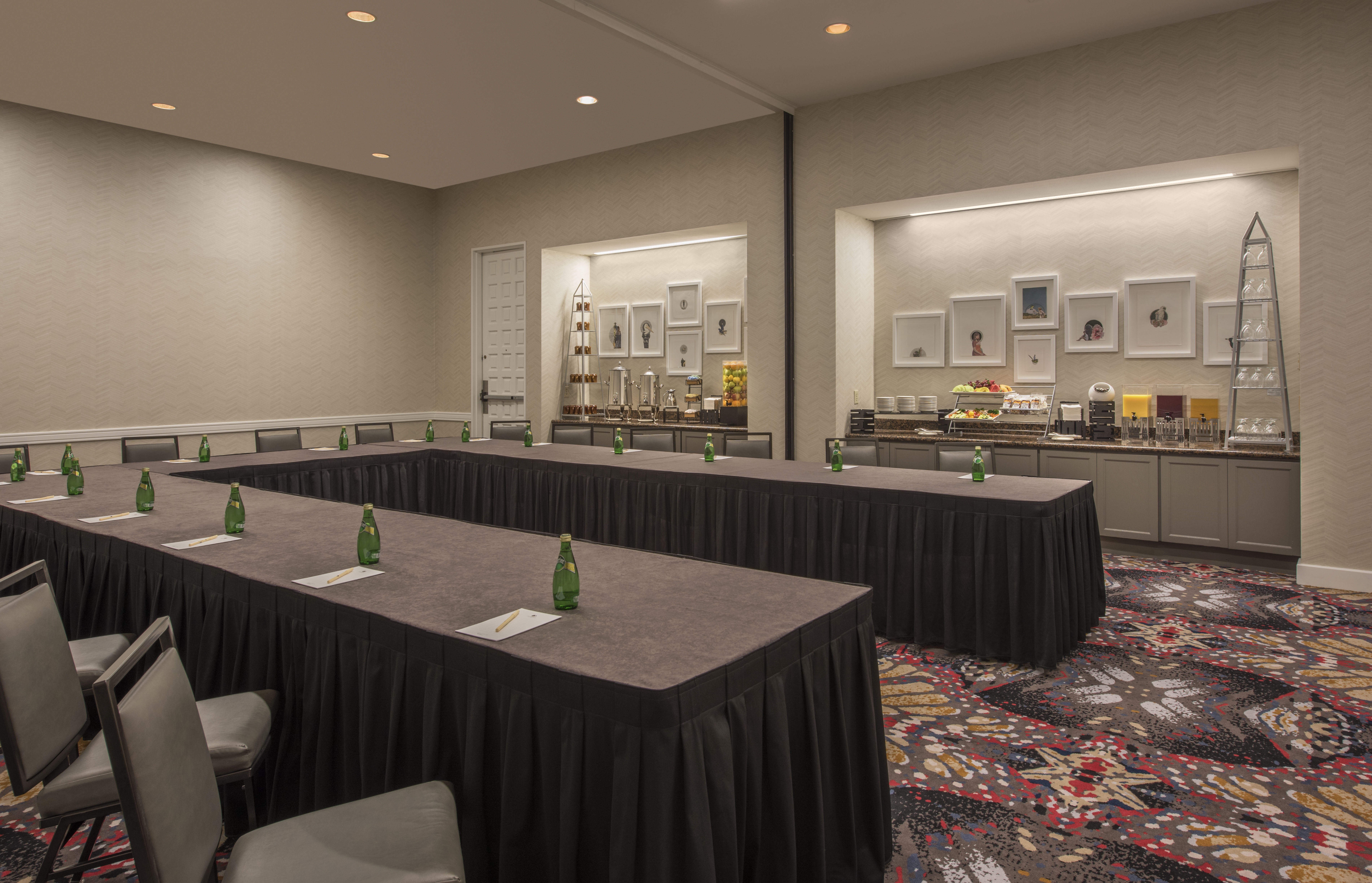 Dewitt Meeting Room With U-Table, Chairs, and Wall Art Above Brightly Lit Refreshment Areas