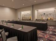 Dewitt Meeting Room With U-Table, Chairs, and Wall Art Above Brightly Lit Refreshment Areas