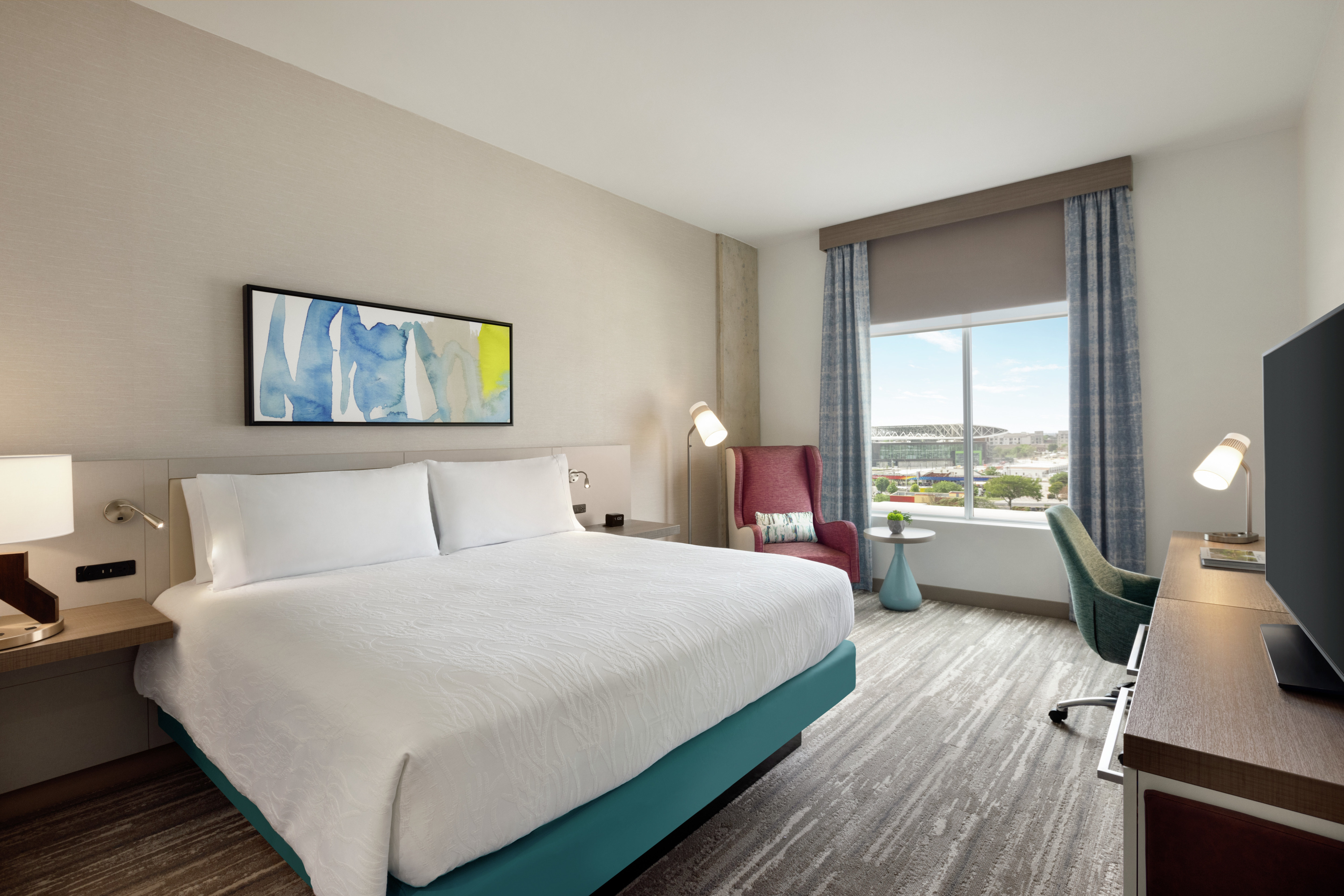Spacious guest room featuring comfortable king bed, work desk, and beautiful city view.