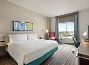 Spacious guest room featuring comfortable king bed, work desk, and beautiful city view.