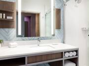 Bright guest bathroom featuring large vanity, light up mirror, and spacious shower.