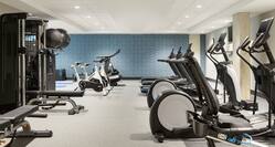 Bright on-site fitness center fully equipped with cardio machines, free weights, and stationary bikes.