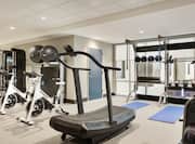 Bright on-site fitness center fully equipped with cardio machines, free weights, yoga mats, and stationary bikes.