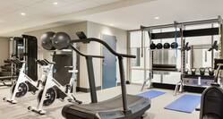 Bright on-site fitness center fully equipped with cardio machines, free weights, yoga mats, and stationary bikes.