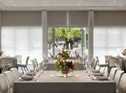 Spacious meeting room featuring wedding setup with beautiful floral center pieces, ample seating, and bright natural light.