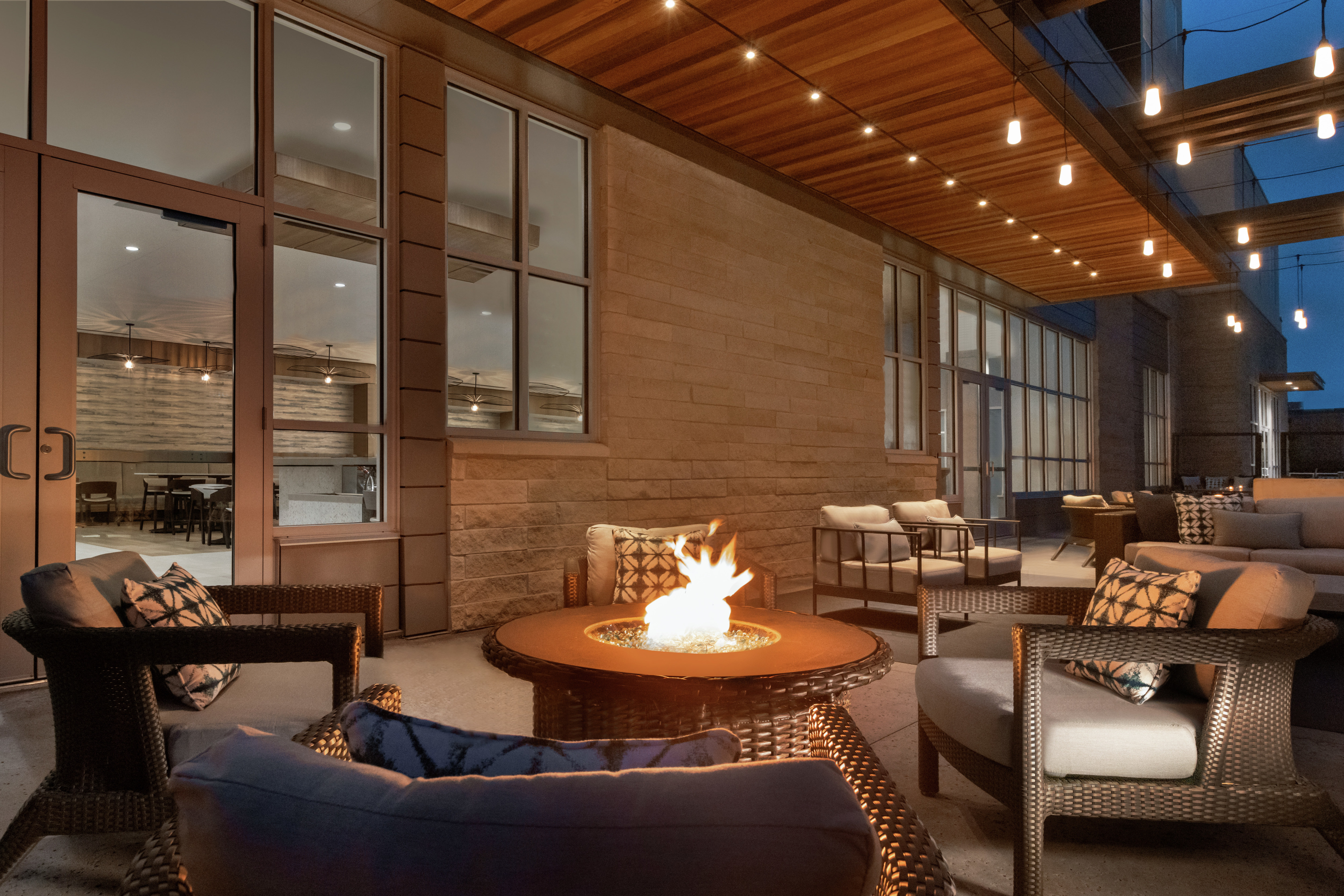 Beautiful outdoor patio in the evening featuring comfortable seating, string lights, and firepit.