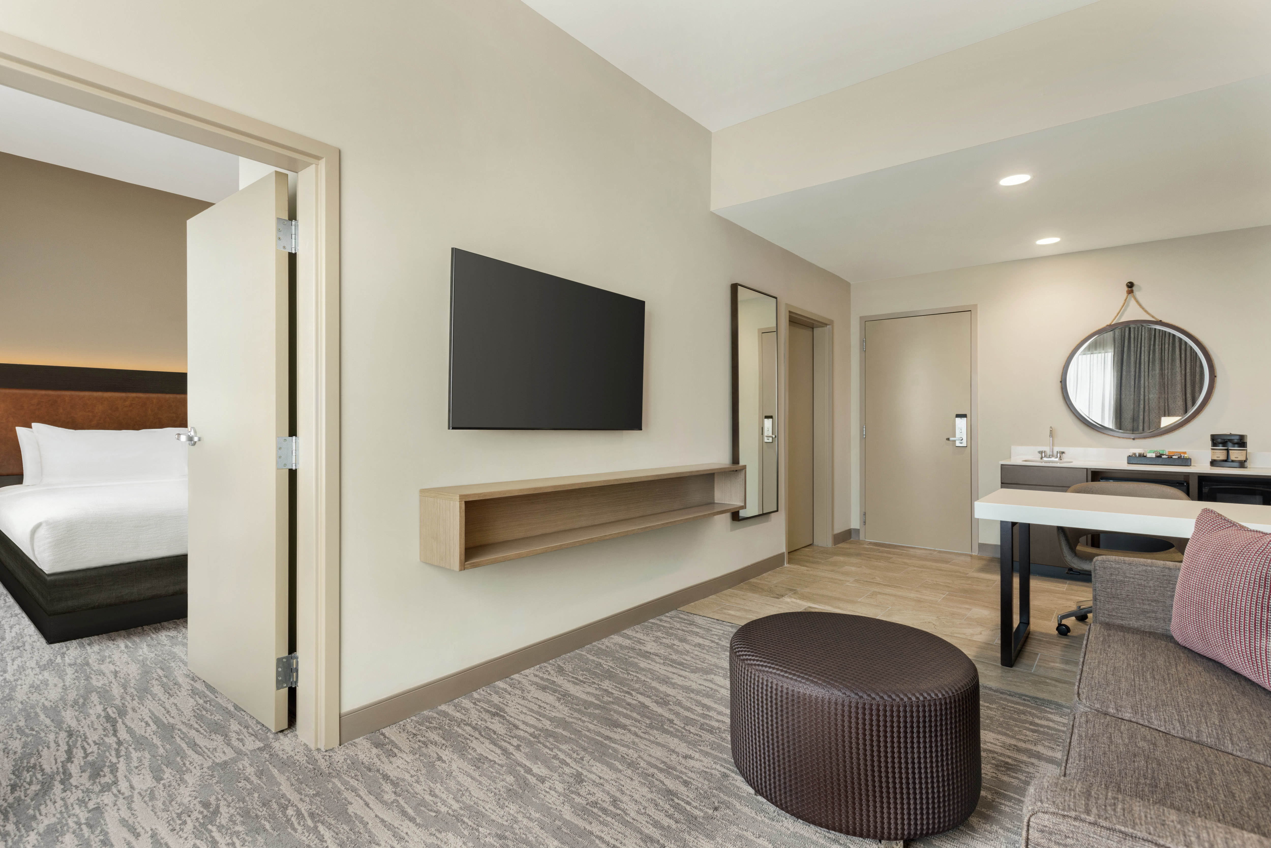 Spacious living area in suite featuring comfortable seating, TV, work desk, and wet bar.