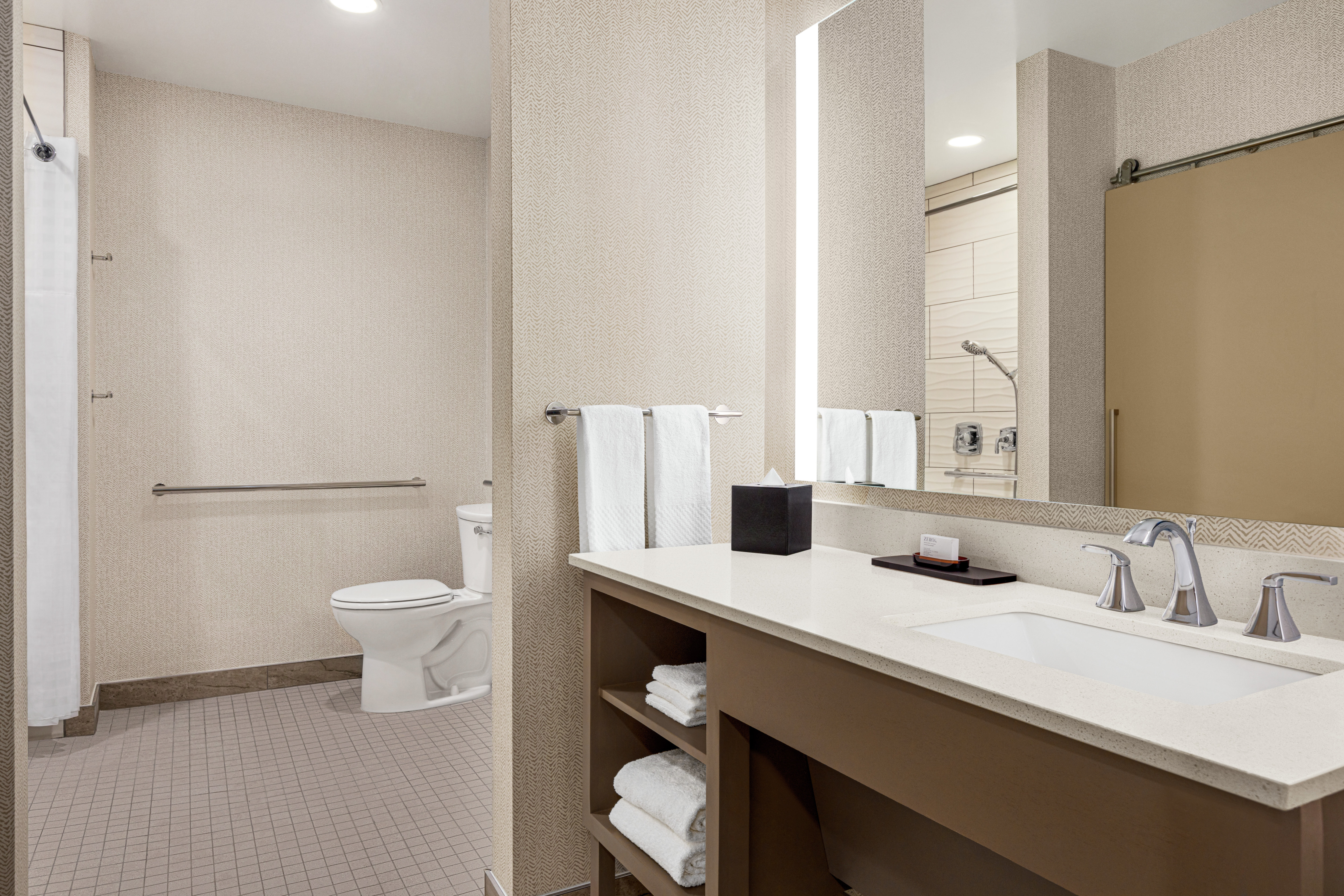 Spacious accessible bathroom featuring large vanity and convenient roll-in shower.