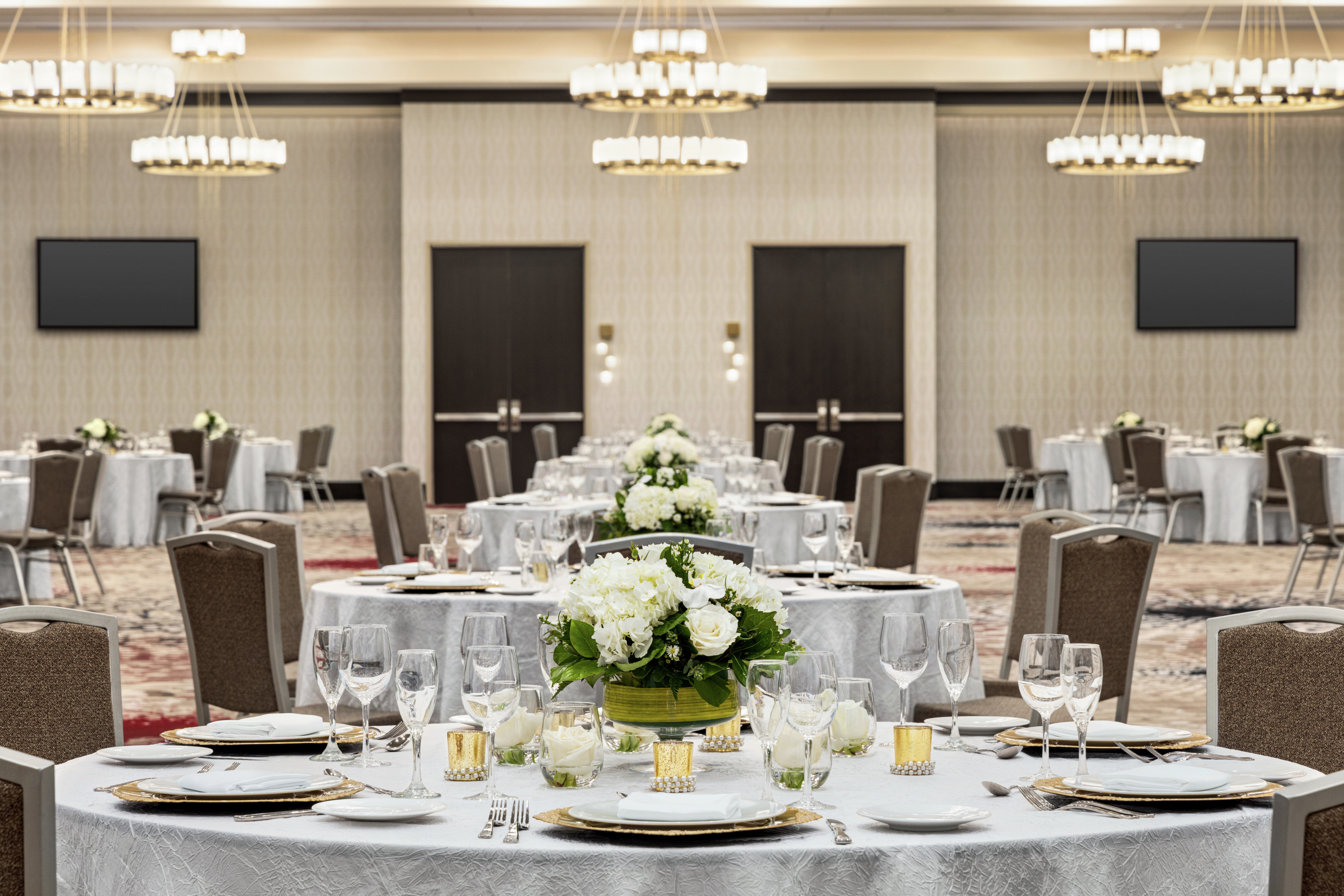 Spacious hotel ballroom featuring wedding setup with stunning centerpieces.