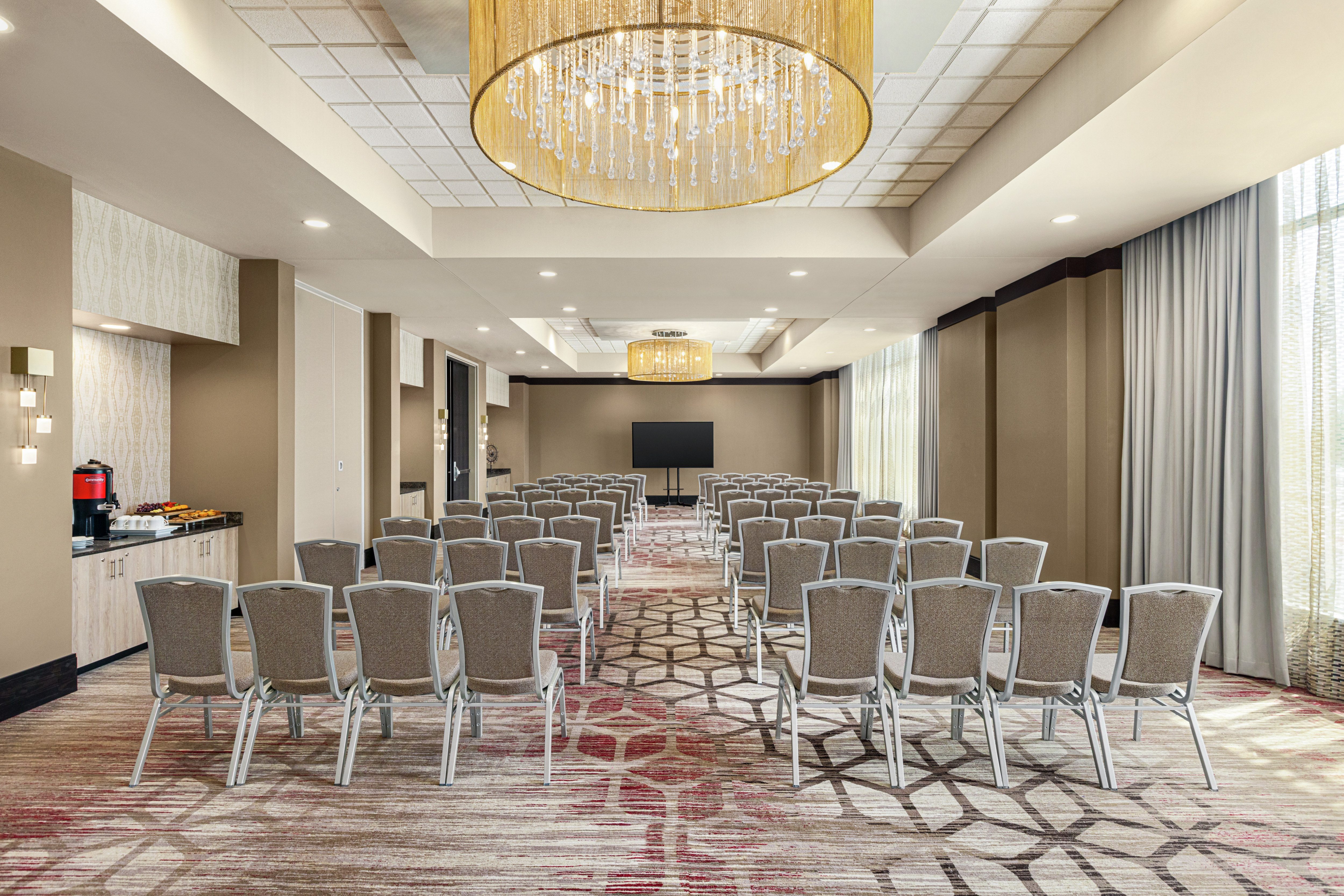 Spacious meeting room featuring a theater style setup, refreshment station, and TV at front of room.