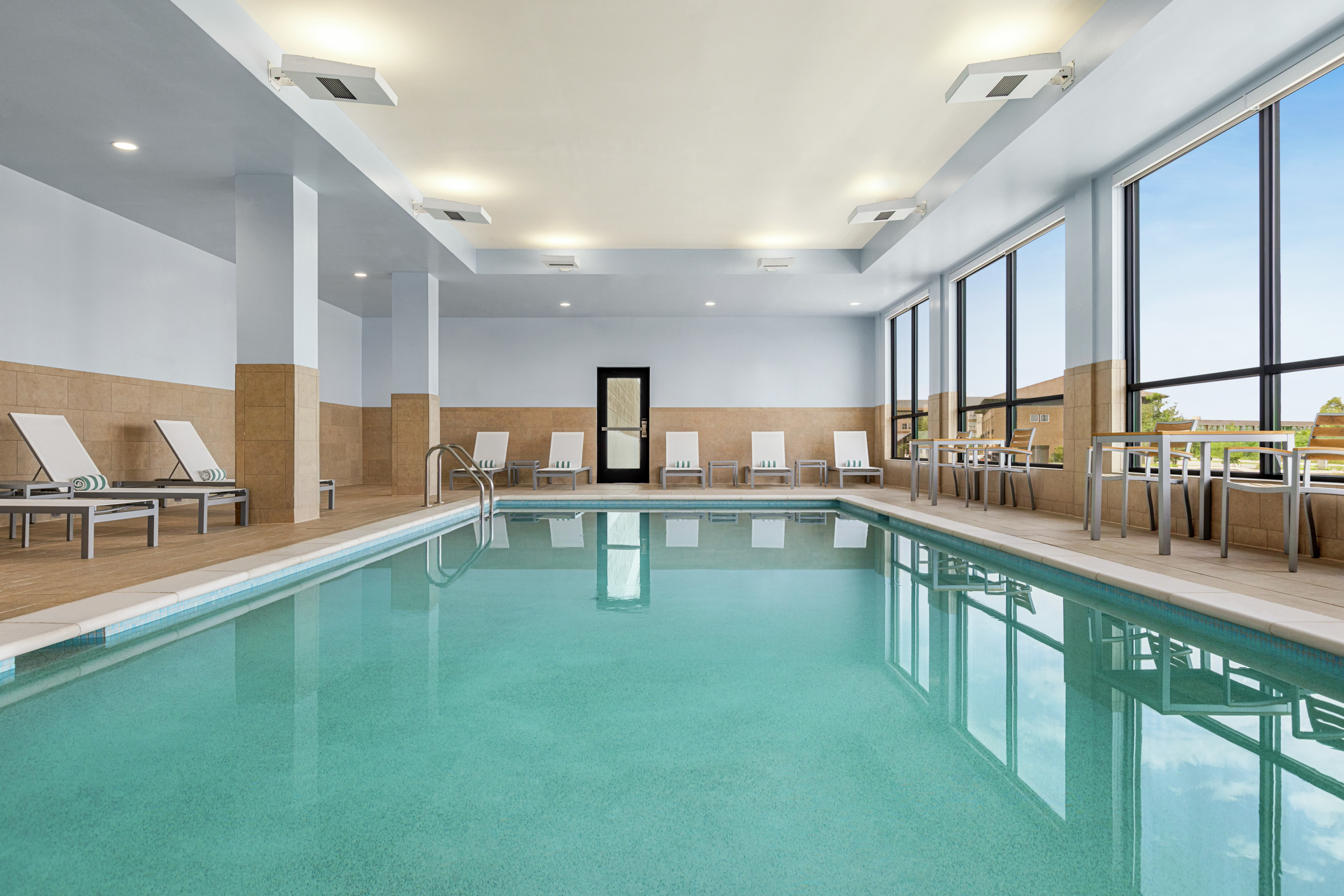 Spacious indoor pool featuring ample seating and large bright windows.