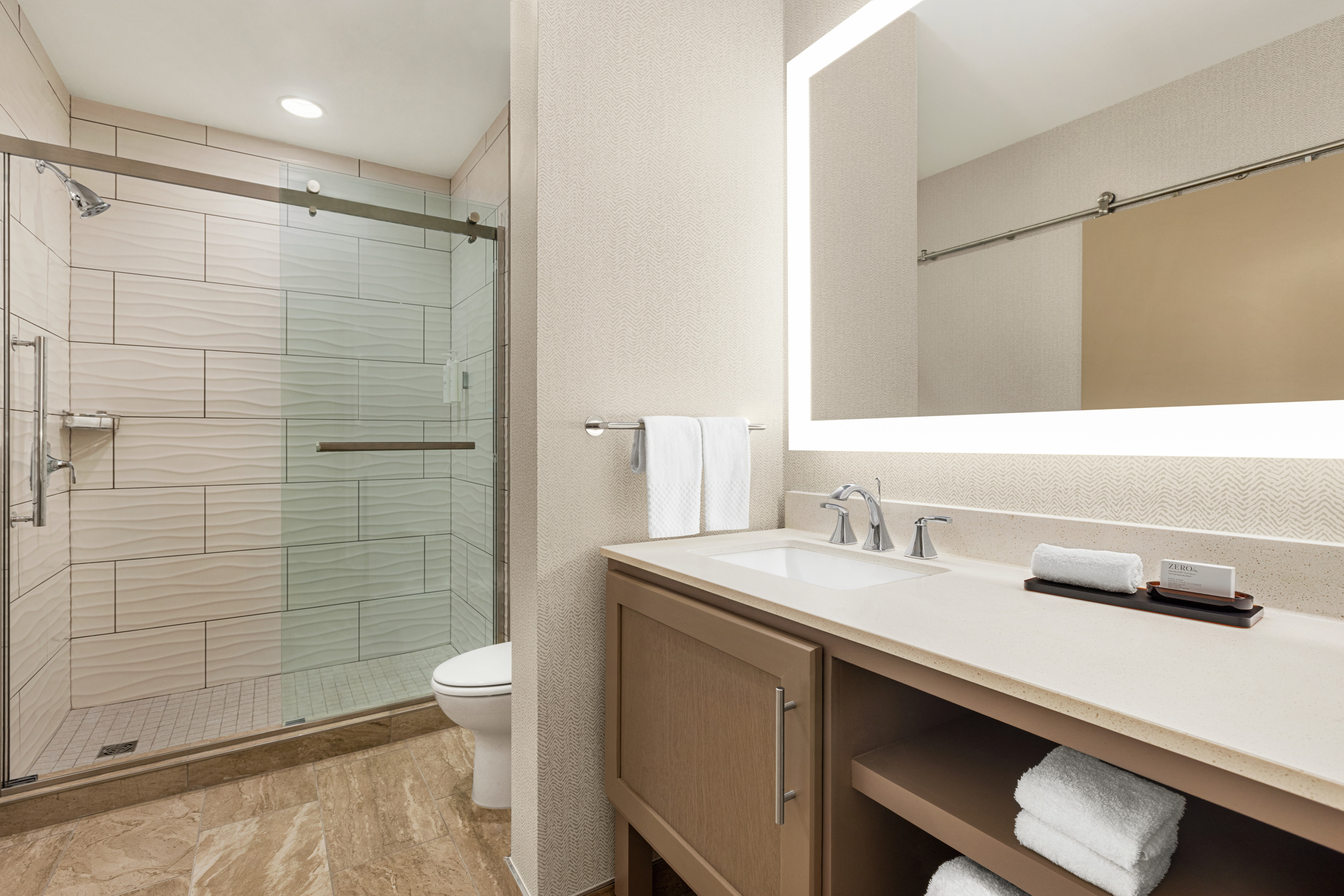 Spacious guest bathroom featuring large vanity, mirror, and walk in shower.