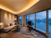 Illuminated Lamps Sofa, Coffee Table, TV in Front of Large Window With Lake View, and Sofa