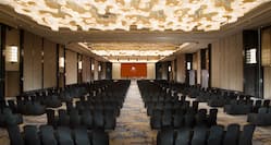  Grand Ballroom Arranged Theater Style With Rows of Black Chairs Facing Projector Screen and Podium