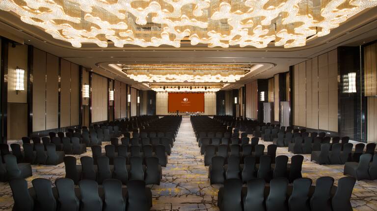  Grand Ballroom Arranged Theater Style With Rows of Black Chairs Facing Projector Screen and Podium