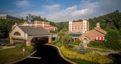 Aerial View of Hotel Exterior, Signage, Landscaping, Porte Cochere and Guest Cars on Parking Lot on a Sunny Day