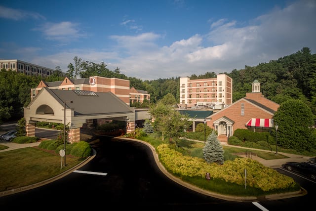 Aerial View of Hotel Exterior, Signage, Landscaping, Porte Cochere and Guest Cars on Parking Lot on a Sunny Day