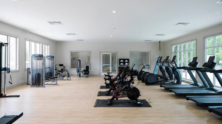 Exercise equipment in the fitness center with outside views on two walls.