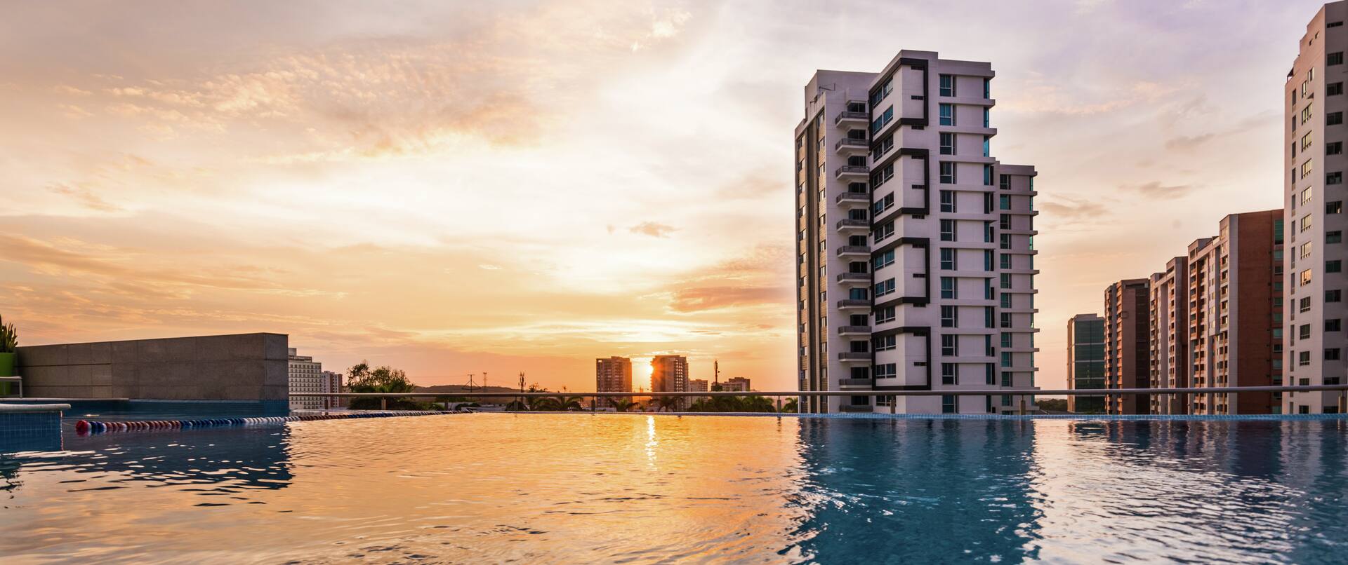 Infinity pool with sunset and views of tall buildings