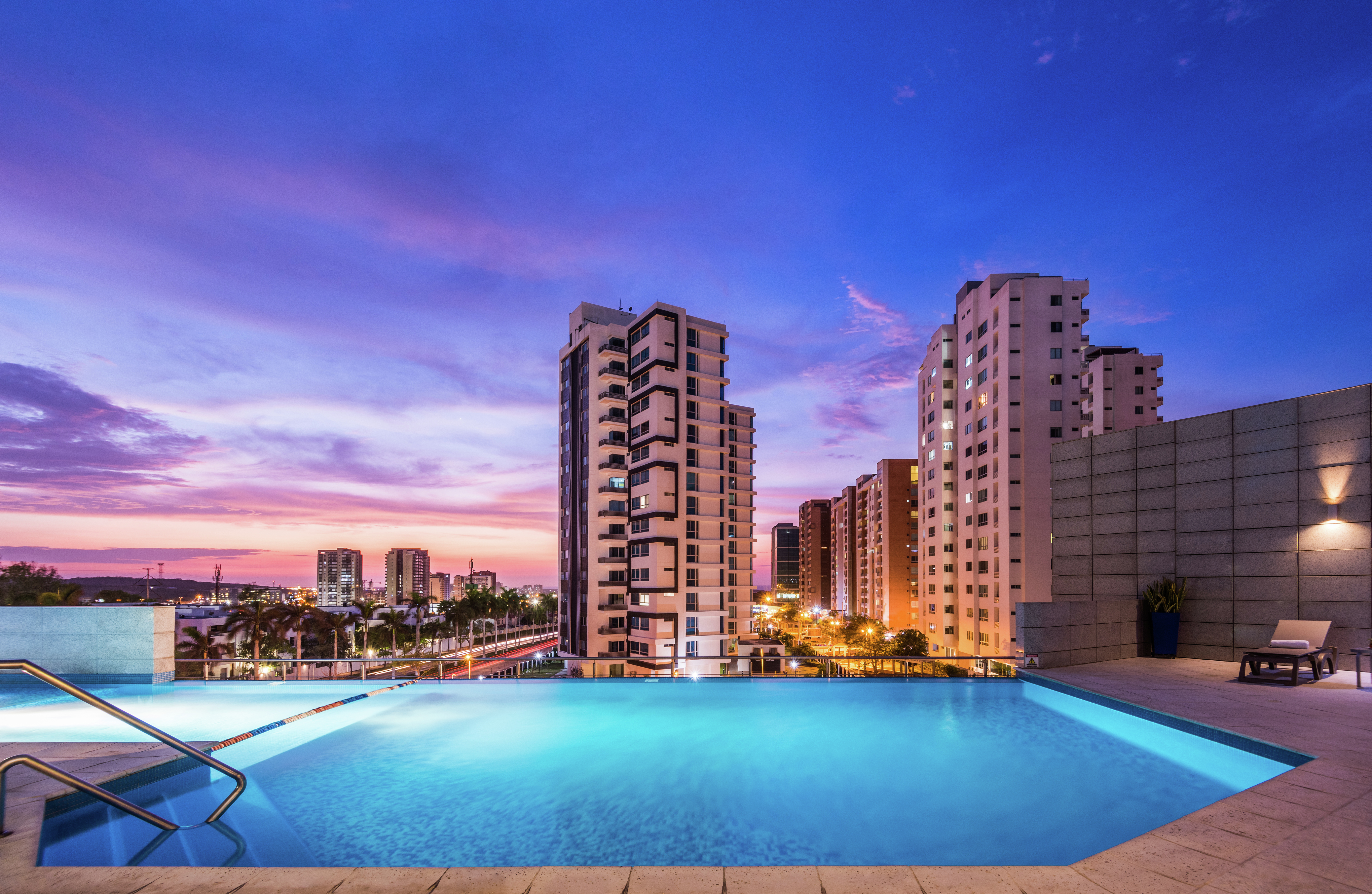 Infinity pool with sunset sky and view of tall buildings