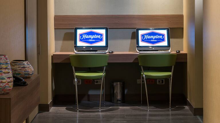 Dos estaciones de trabajo con computadoras y sillas verdes en el centro de negocios