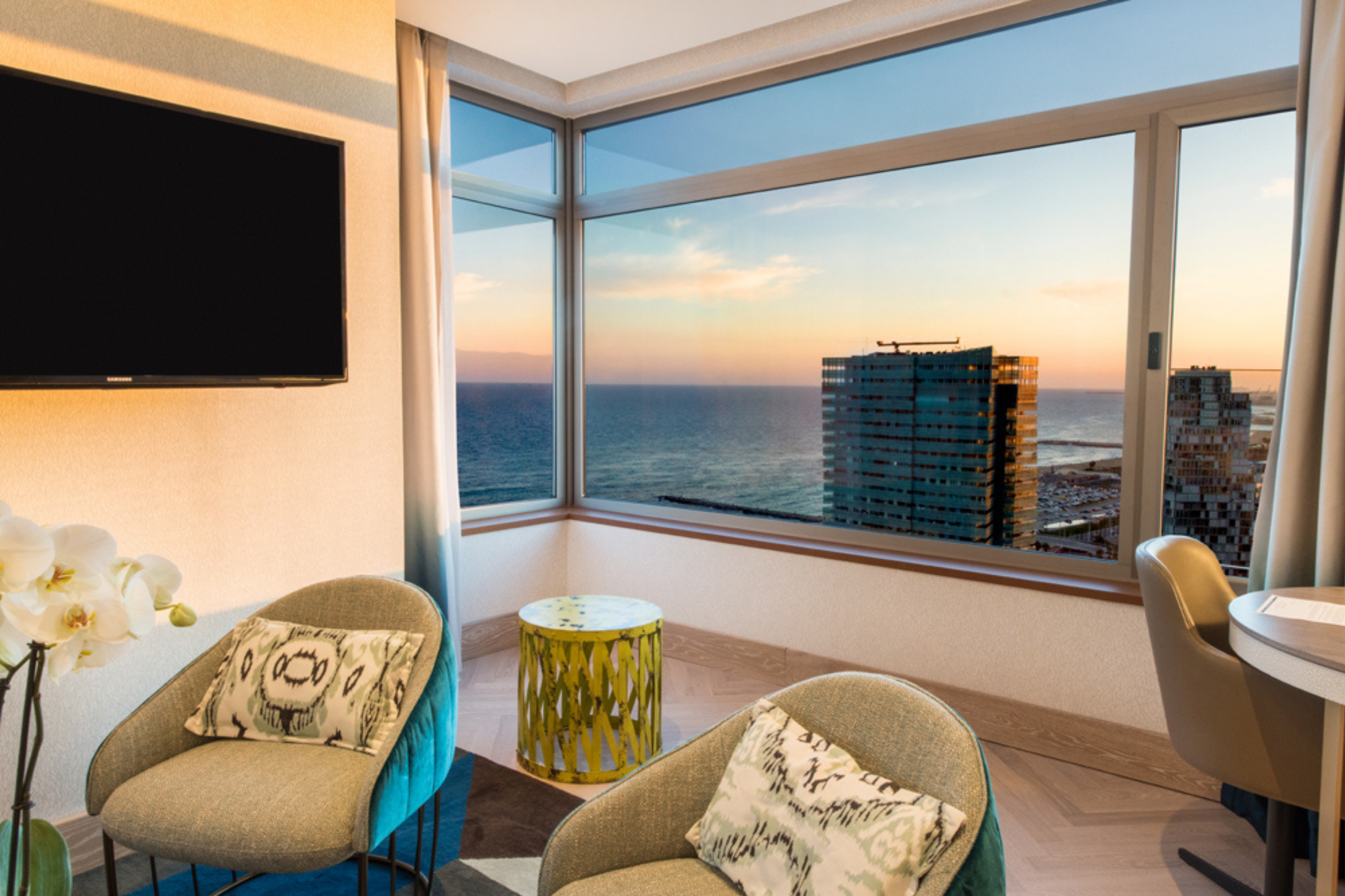 Sala de estar de la suite con televisor de alta definición y vista a la ciudad y al mar